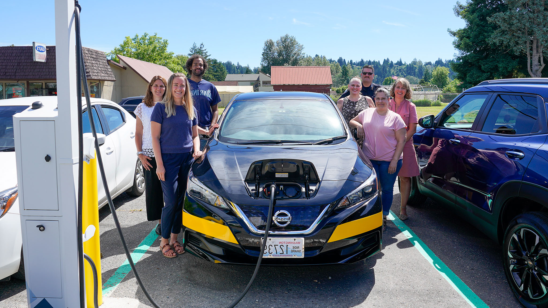 King County Metro and PSE employees pose with a new electric Community Van and charger installed with the help of our Equity Focused pilot.